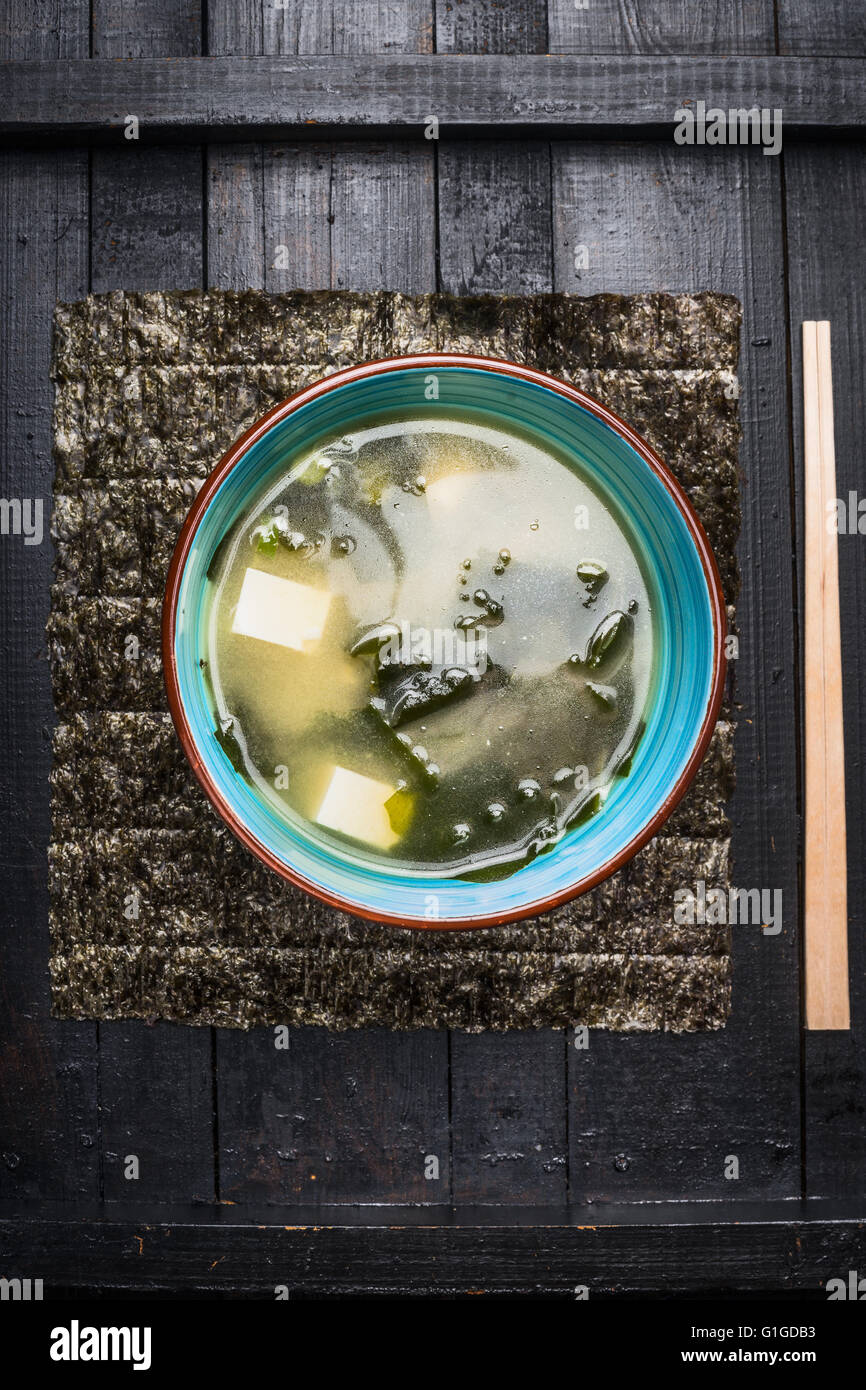 Miso soup in blue bowl on dark rustic background, top view Stock Photo