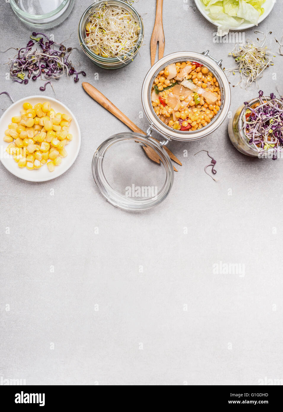 Glass jar salad and vegetables ingredients on light stone background, top view, place for text.  Clean eating, vegetarian or die Stock Photo