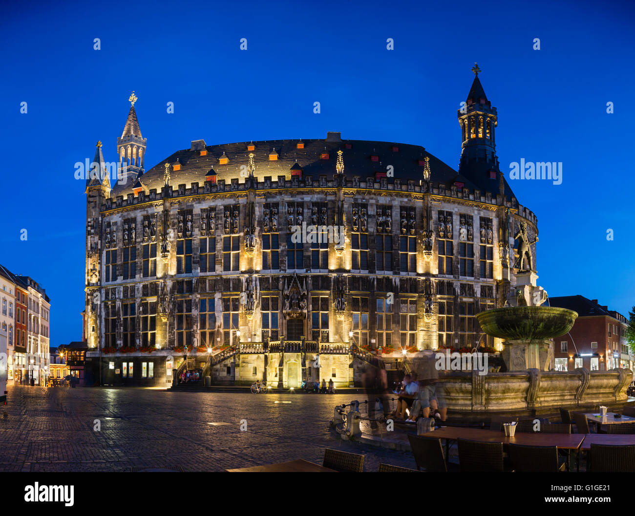 Panoramic view of the historic town hall of Aachen, Germany with night blue sky and the Karlsbrunnen in the foreground. Stock Photo