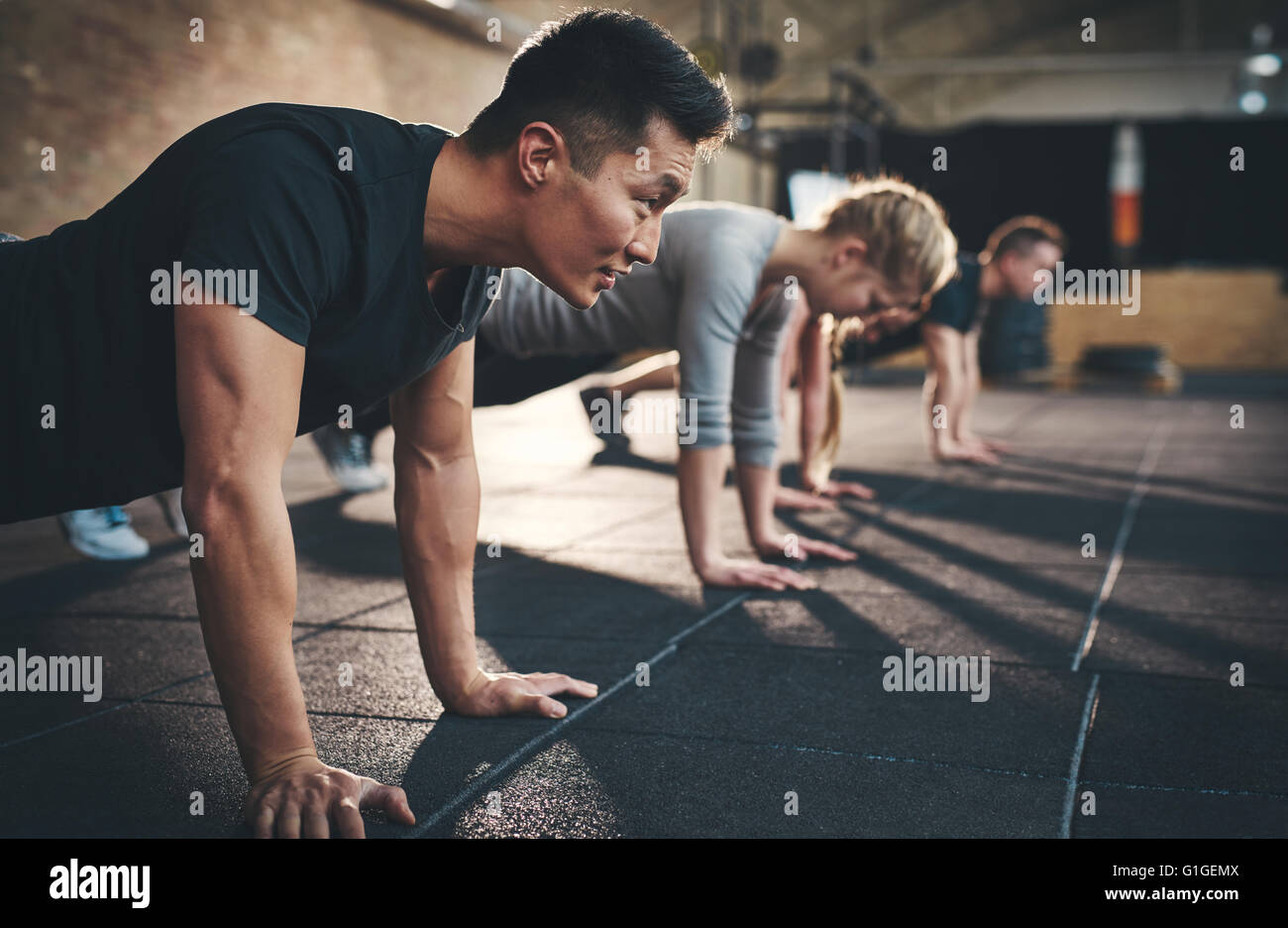 Fit young people doing pushups in a gym looking focused Stock Photo