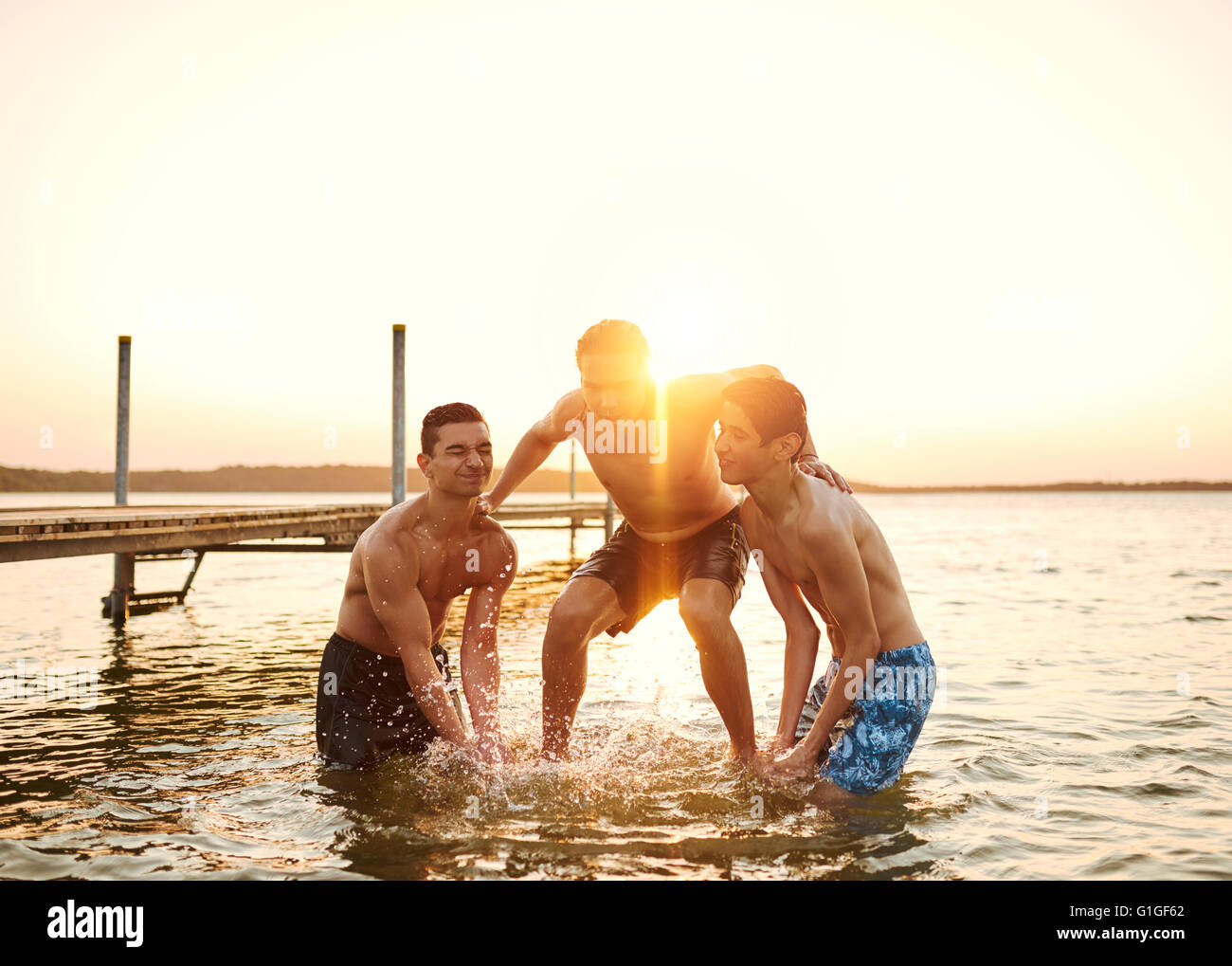 Good friends swimming at the beach and throwing each other in the water