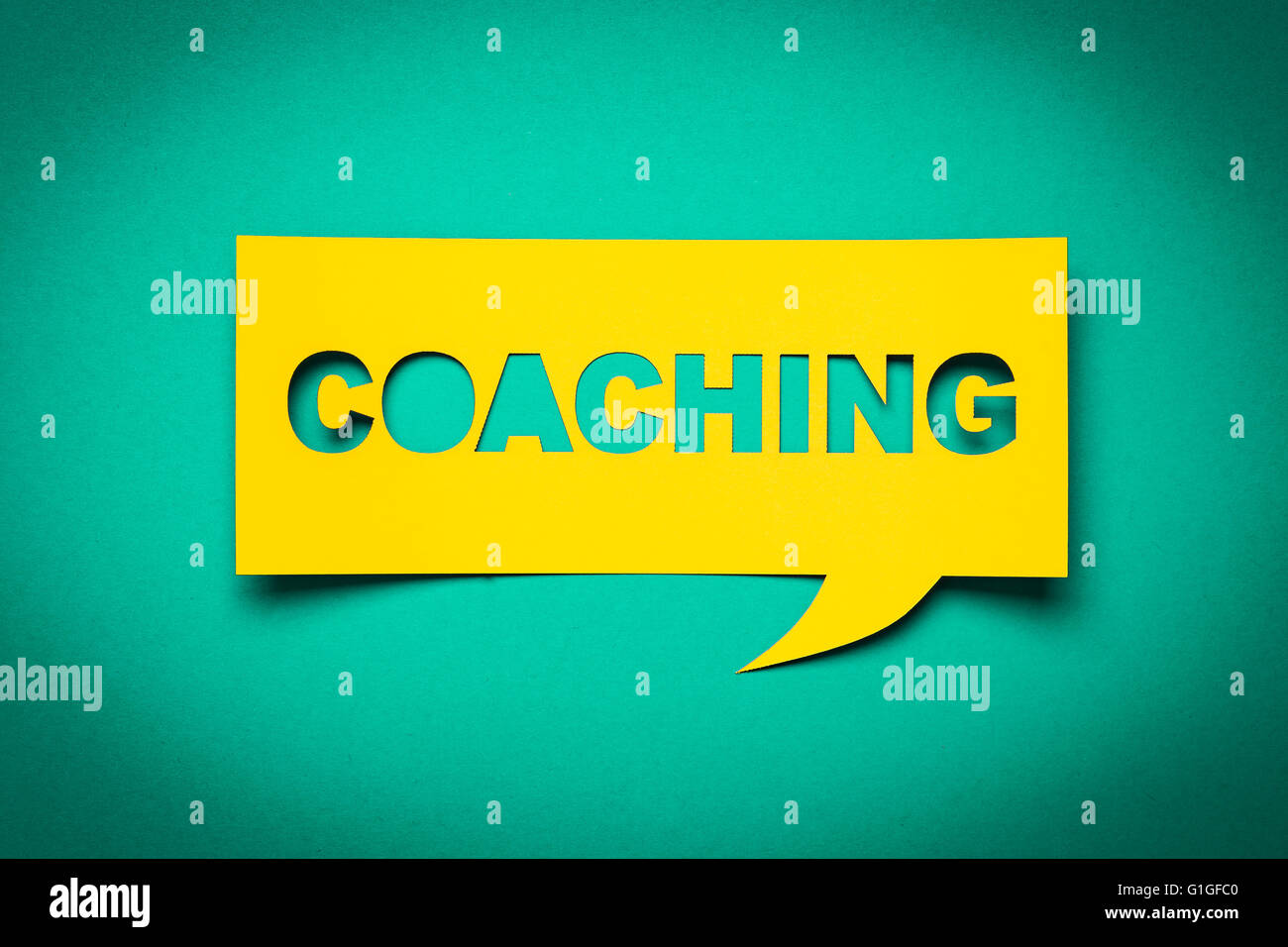 Bubble speech with cut out phrase 'coaching' in the paper. Stock Photo