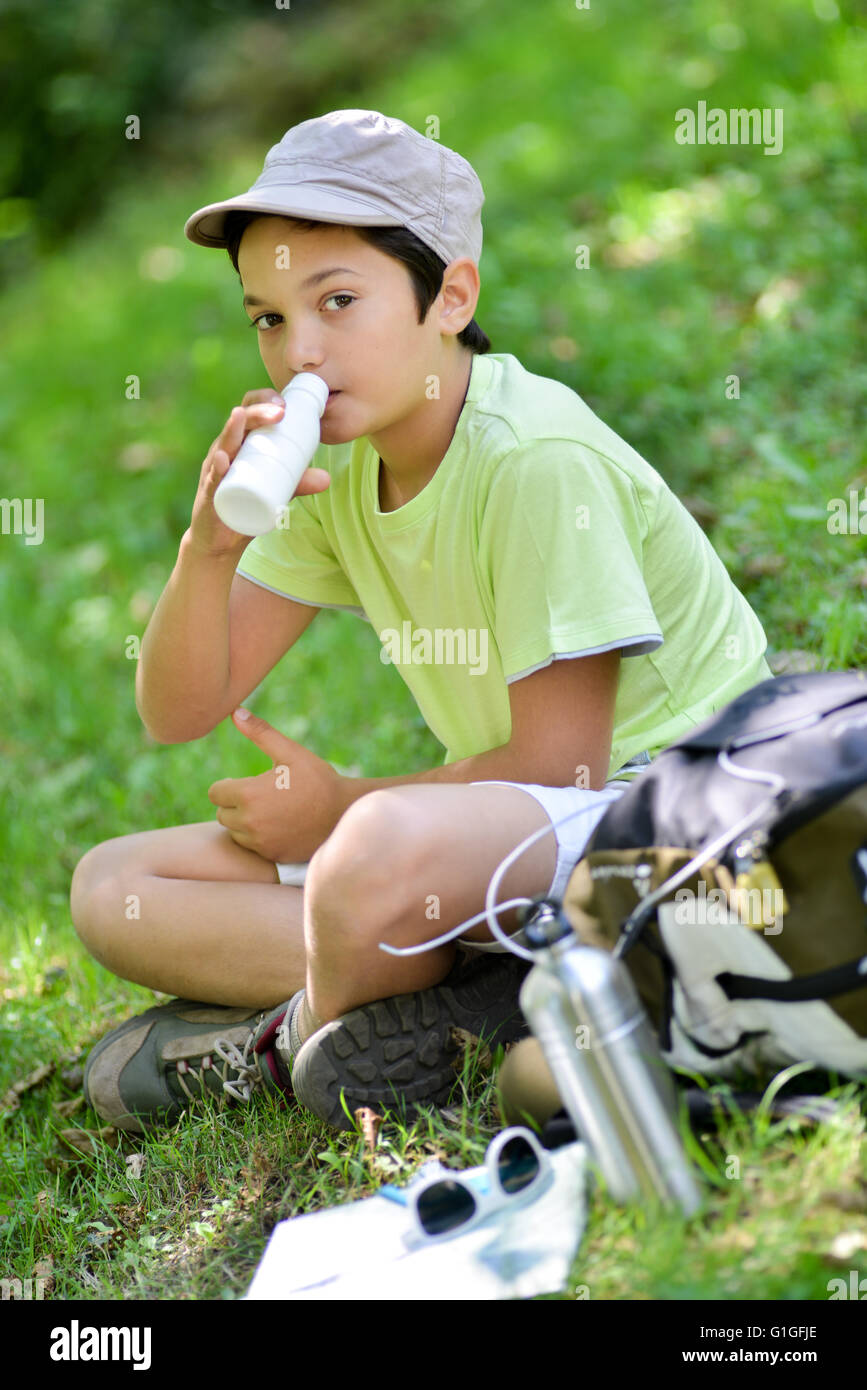 Young boy sitting in the grass and drinking a milk drink Stock Photo