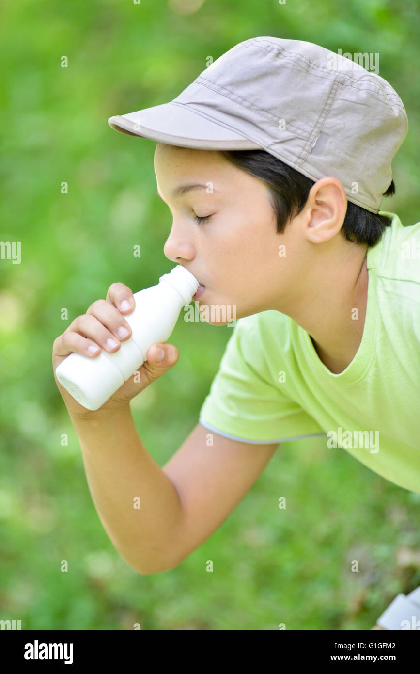 Young boy sitting in the grass and drinking a milk drink Stock Photo