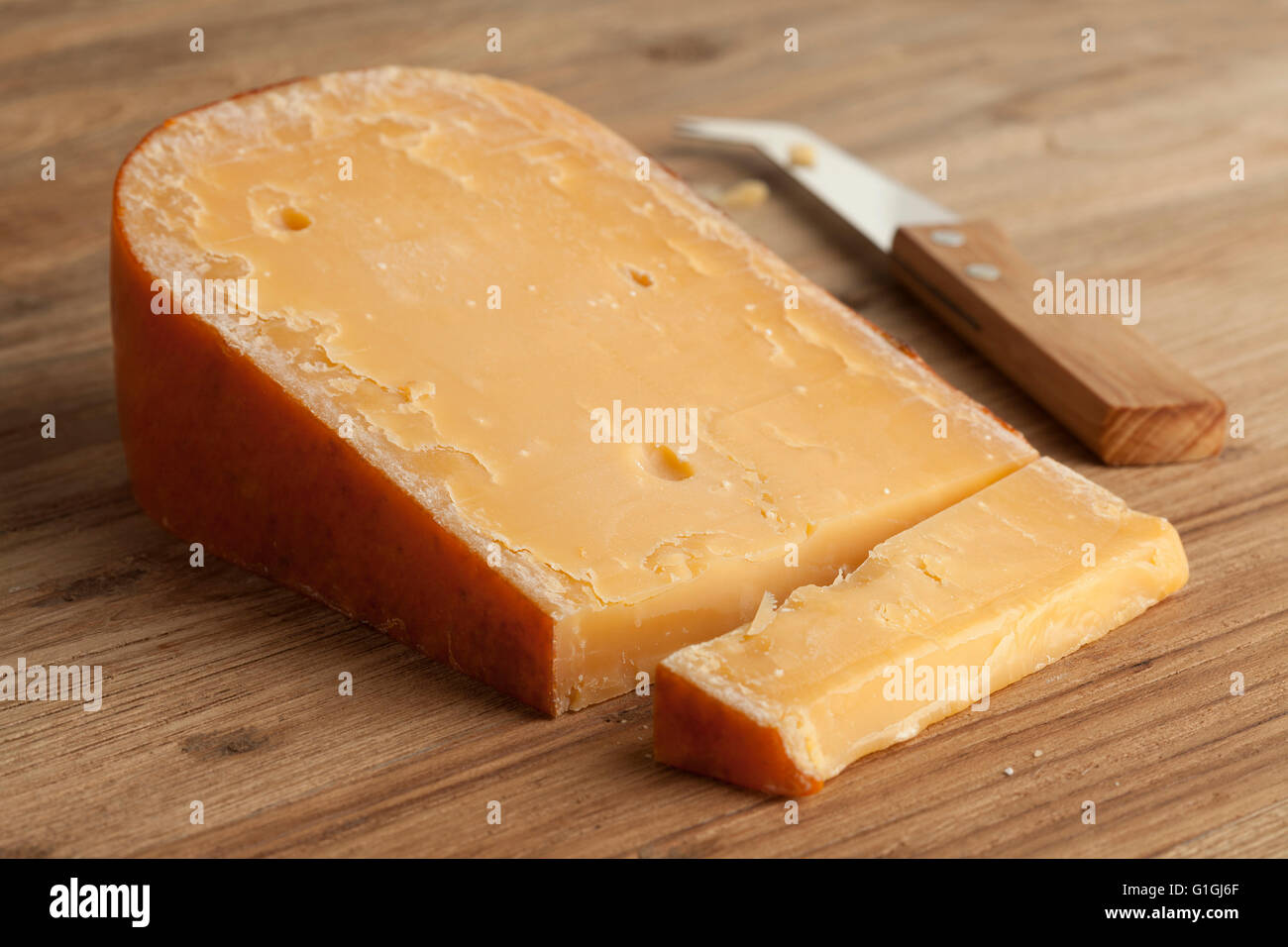 Piece of three year old Gouda cheese on a cheeseboard Stock Photo