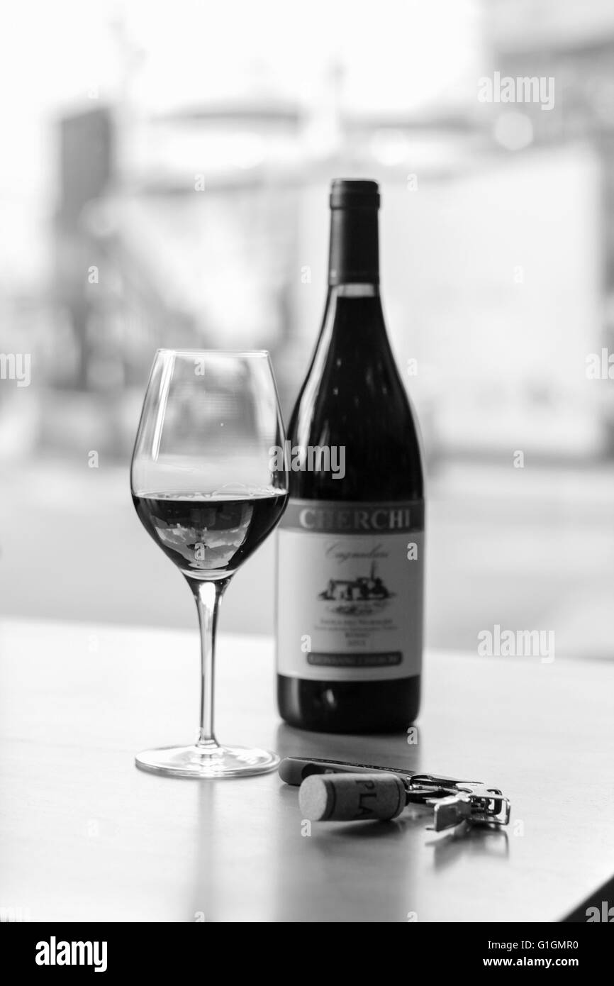 A black and white image of a bottle opener a wine glass and a bottle. Stock Photo