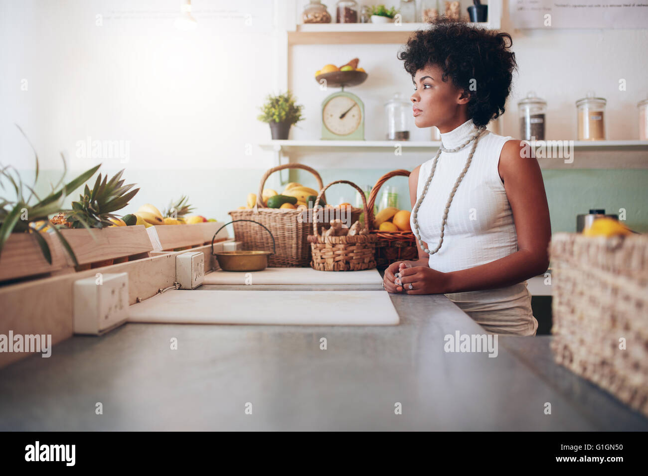 Side portrait of beautiful young woman behind juice bar counter