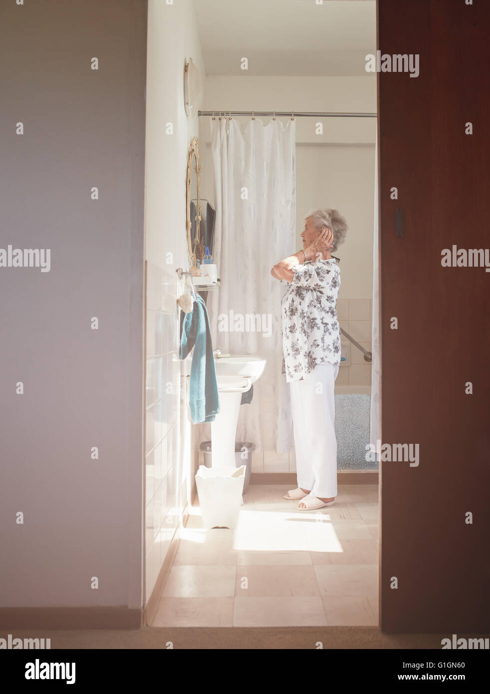 Full length indoor shot of elderly woman getting ready at dresser. Senior female getting ready in bathroom. Stock Photo