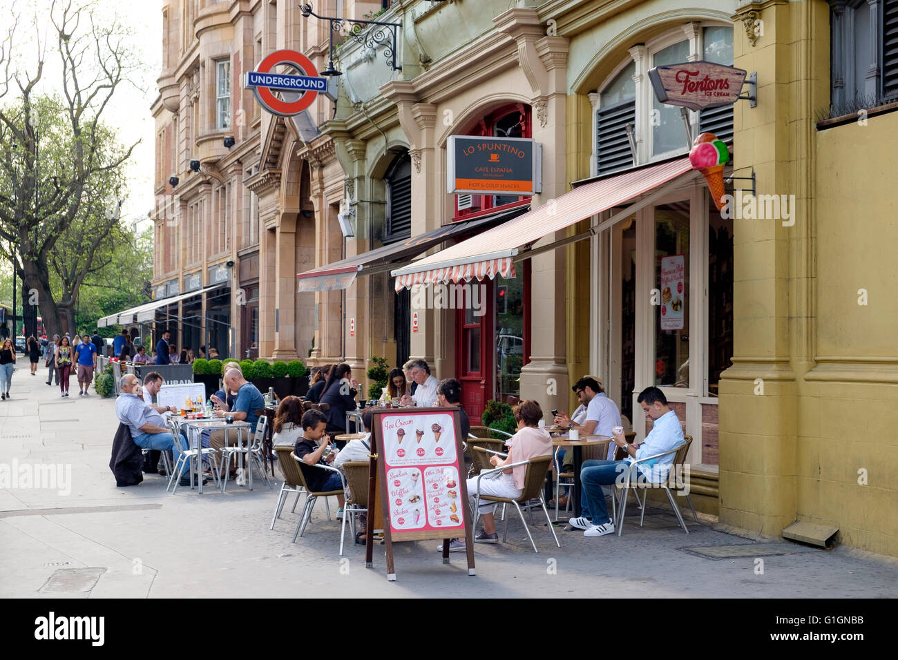 People sitting at a street cafe on Bayswater Road, London, UK outside