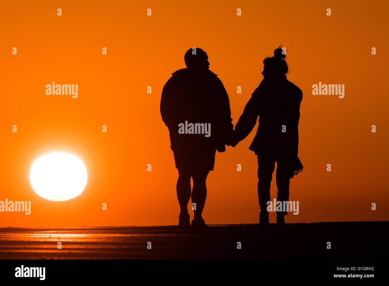 Aberystwyth , Wales UK, Saturday  14 May 2016   UK weather: A spectacular sunset at the end of day of clear skies and bright sunshine, as a couple  walk hand in hand  along the harbour in   Aberystwyth on the Cardigan Bay coastline of west wales.  photo Credit:  Keith Morris/Alamy Live News Stock Photo