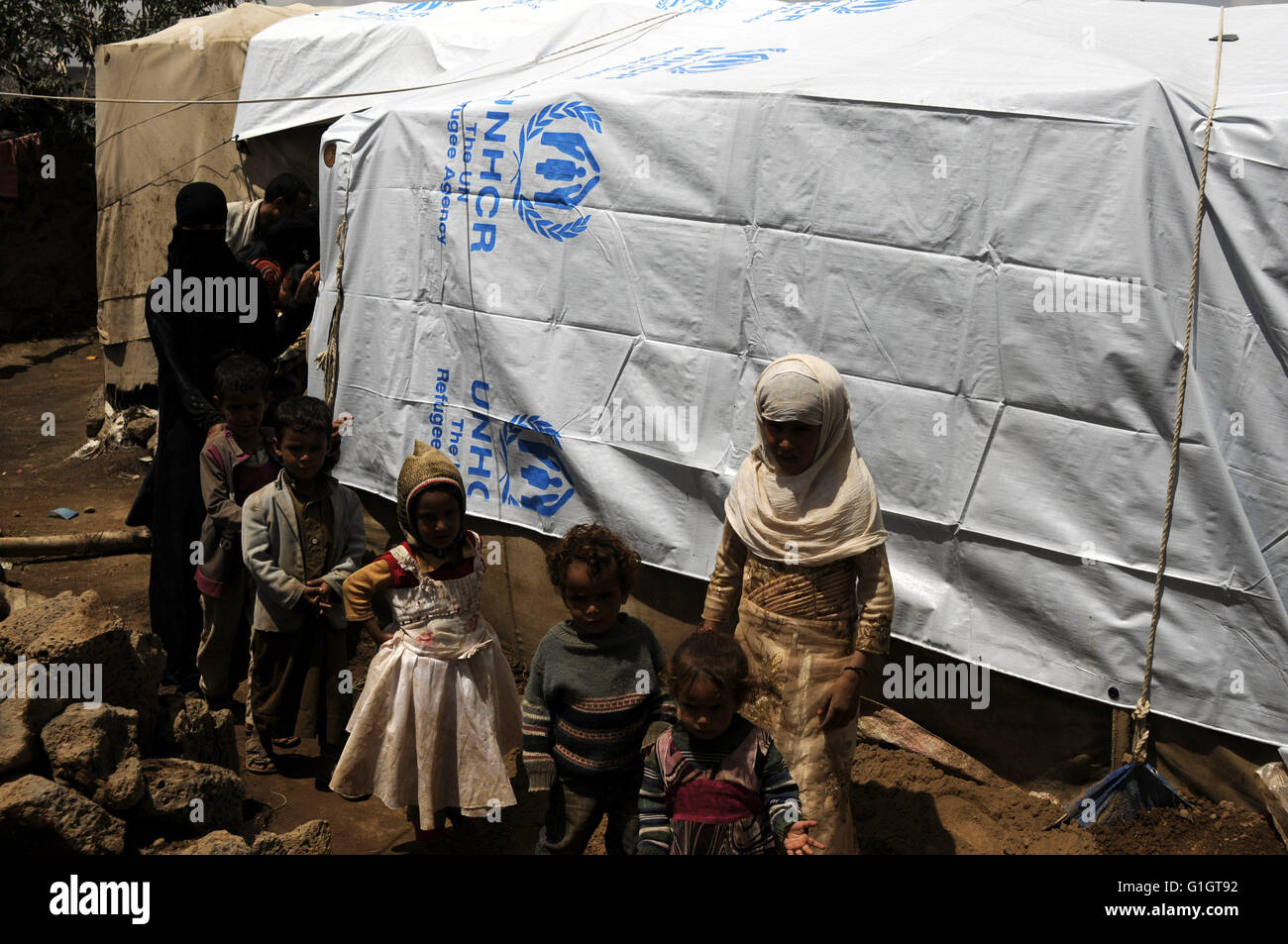 Sanaa, Yemen. 14th May, 2016. Yemeni internally displaced family stand outside their makeshift shelter at a camp on the outskirts of Amran province, Yemen, on May 14, 2016. The ongoing conflict in Yemen has forcibly displaced more than 2.4 million people in Yemen. © Hani Ali/Xinhua/Alamy Live News Stock Photo