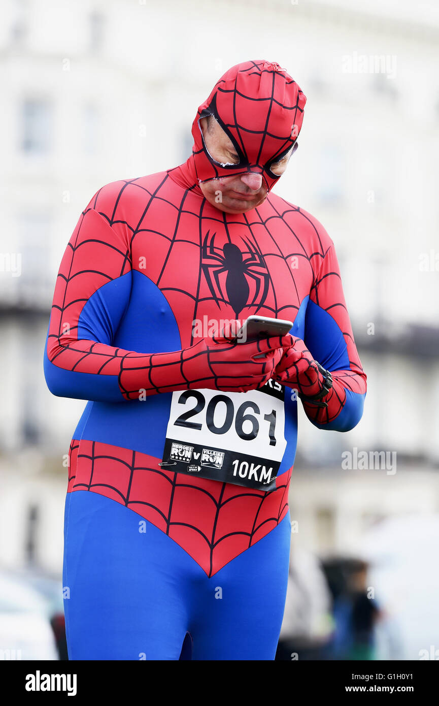 Hove Brighton UK 15th May 2016 - Time for Spiderman to send a message before taking part in the Heroes v Villains Save the Day charity run along Hove seafront today raising money for Pass It On Africa  Credit:  Simon Dack/Alamy Live News Stock Photo