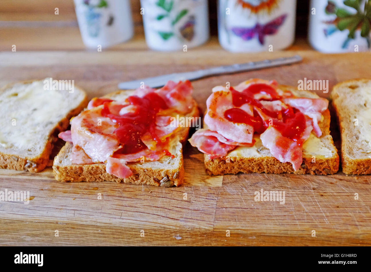 Making a bacon sandwich in brown bread with tomato ketchup or sauce Stock Photo Alamy