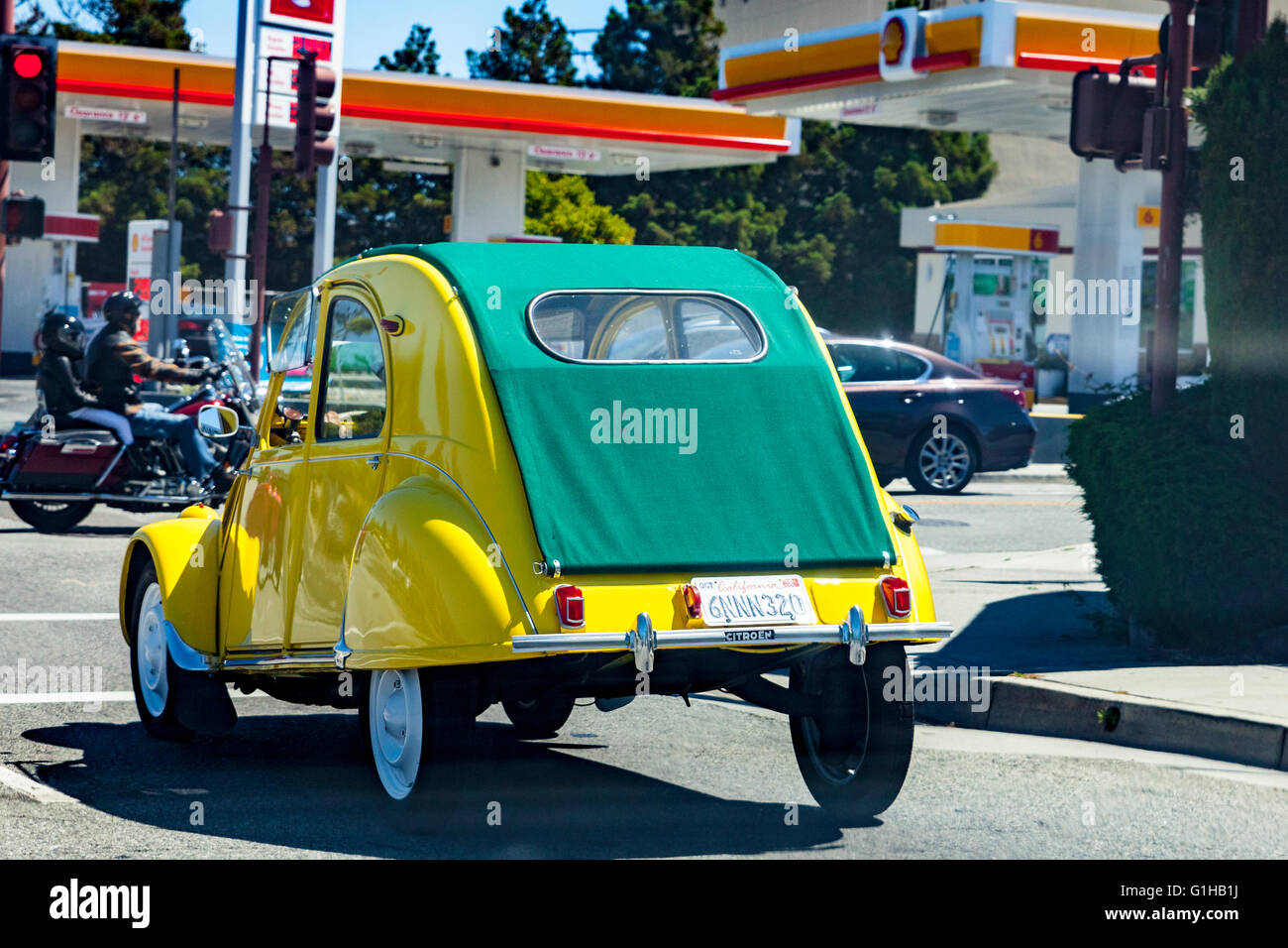 A brightly colored Citroen 2CV driving on El Camino Real in San Carlos California a rare sight in California Stock Photo