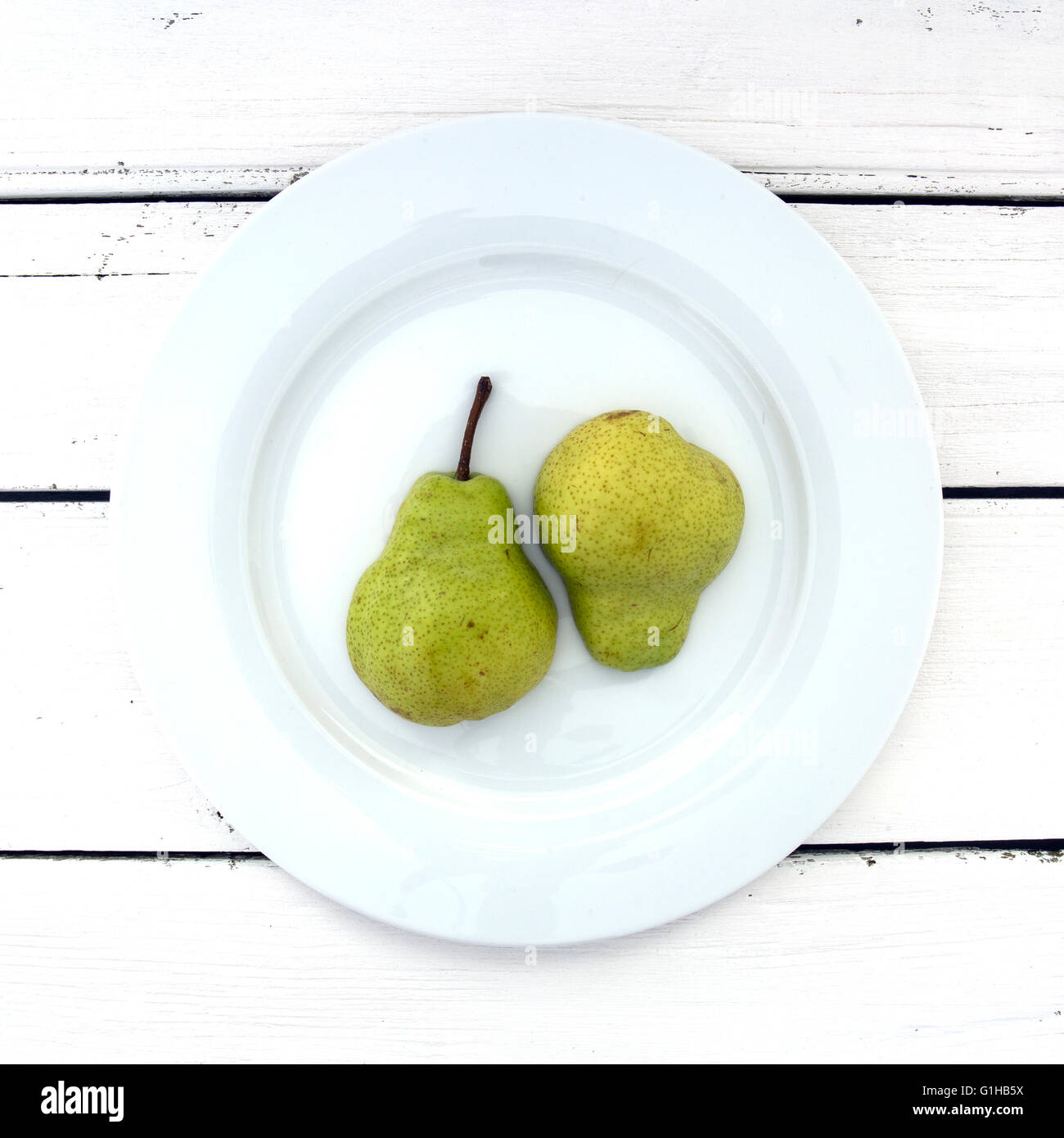 Two Pear Half's on a white plate over a retro white wooden background Stock Photo