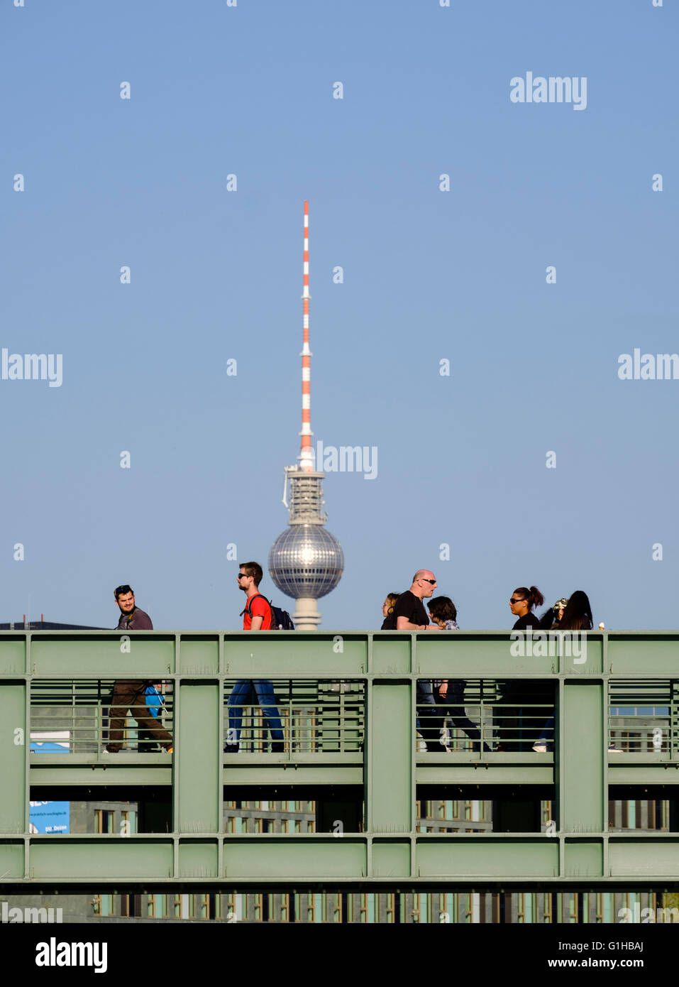 Pedestrians walk over footbridge crossing River Spree with Fernsehturm , television tower, to rear in Berlin Germany Stock Photo