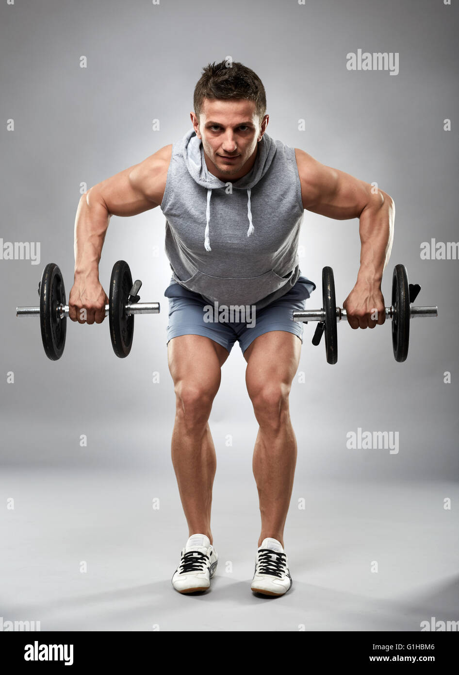 Man doing dumbbell row over gray background in studio Stock Photo - Alamy