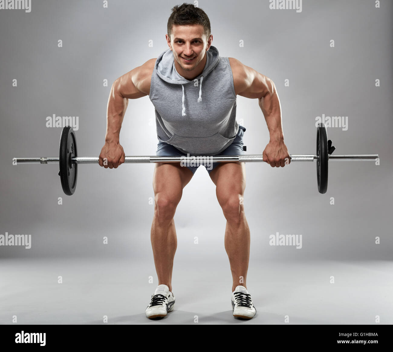 Man doing back workout, barbell row in studio over gray background