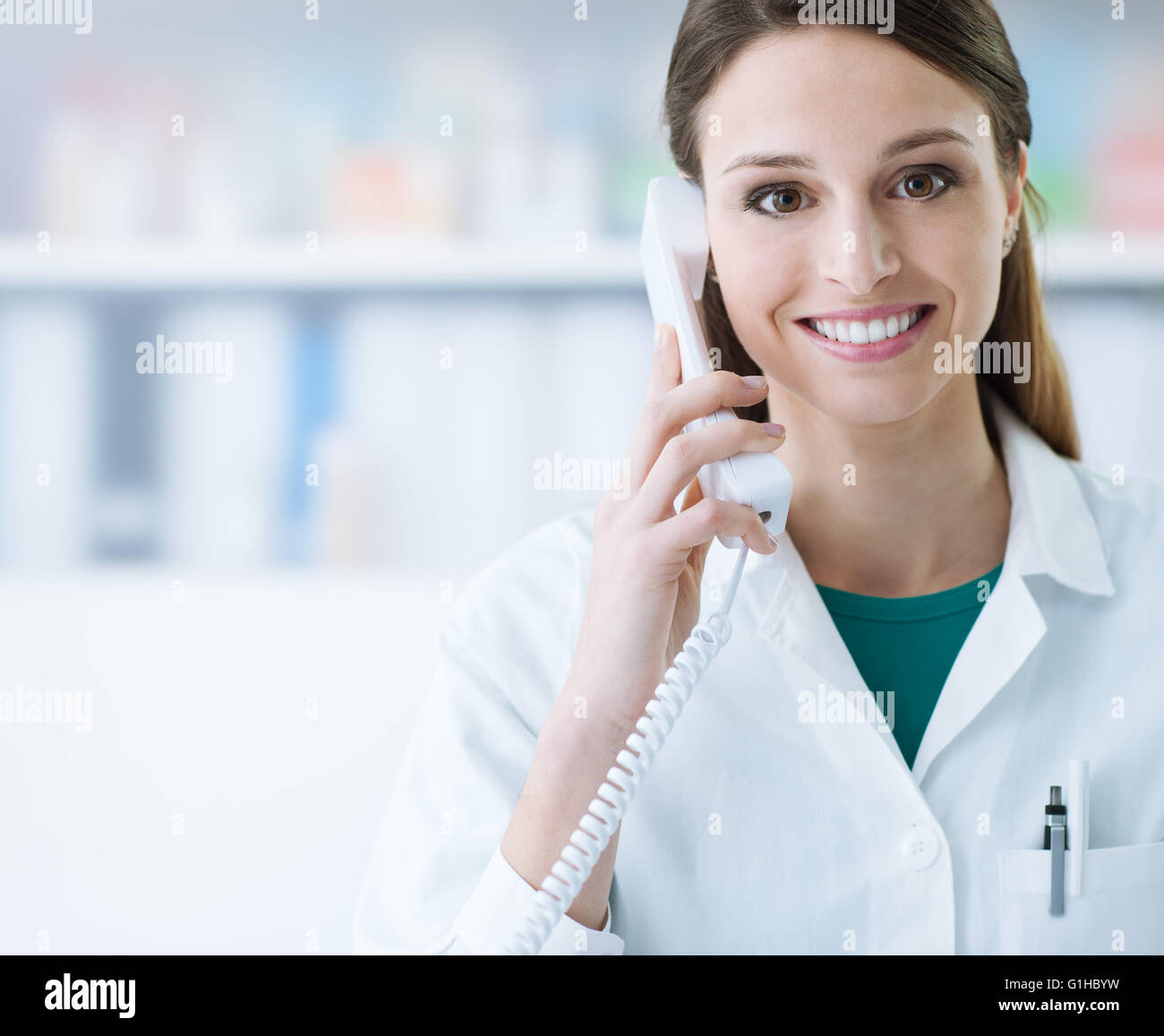 Smiling female doctor holding a receiver and answering phone calls, medical service Stock Photo