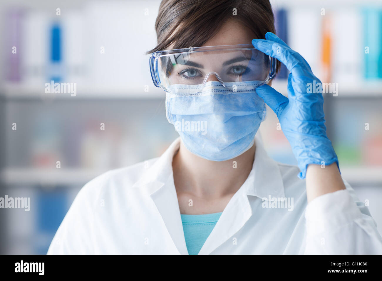 Doctor wearing glasses, surgical mask and gloves, medical procedures and hygiene concept Stock Photo