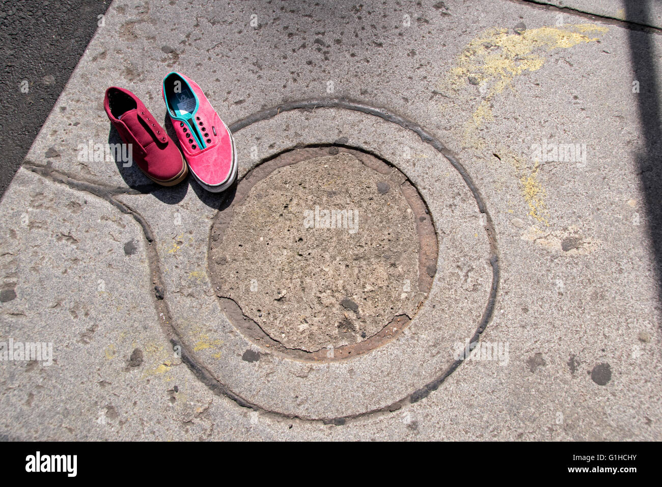 Mysterious image of two unlaced different shoes on the cement sidewalk in New York City. Stock Photo
