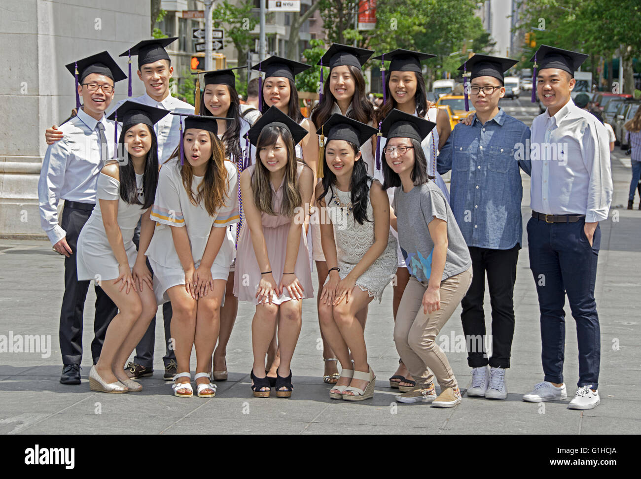 Asian NYU graduates wearing their graduation caps pose for a group photo in Washington Square Park in New York City Stock Photo