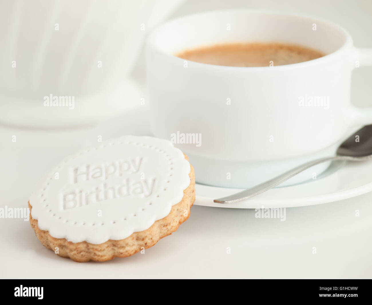Close up of coffee cup and fondant covered cookie. Happy birthday decoration on top. Stock Photo