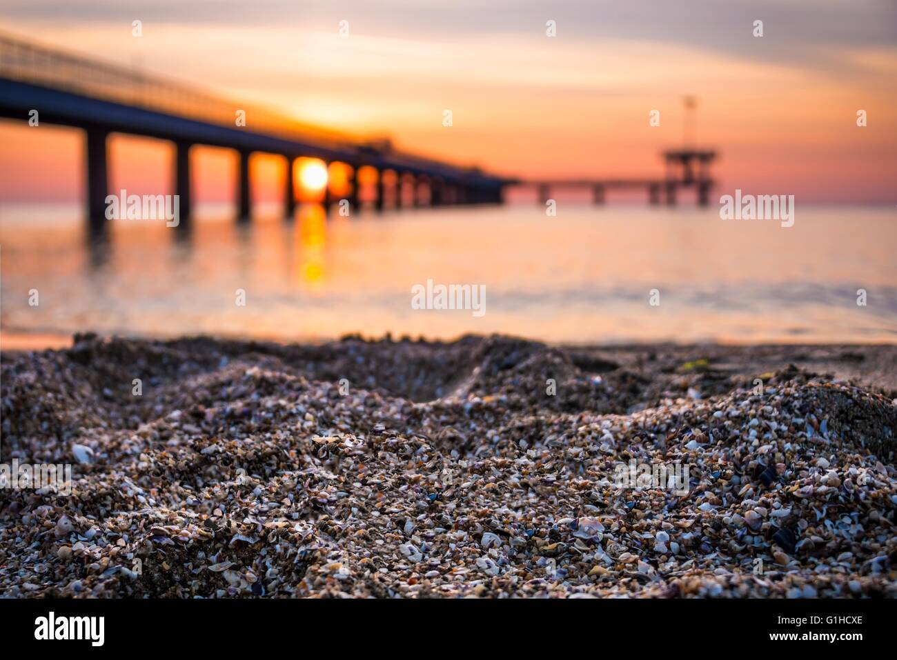 Sand on the beach. Blurred background of bridge and sunrise. Stock Photo