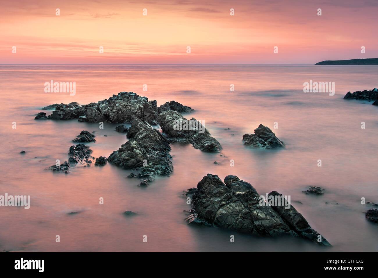 Colorful sunrise over the sea viewed from the beach rocks Stock Photo