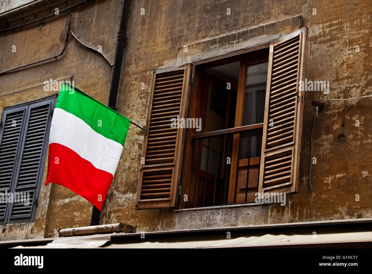 Opened window with the Italian flag on facade of old building in Rome, Italy Stock Photo