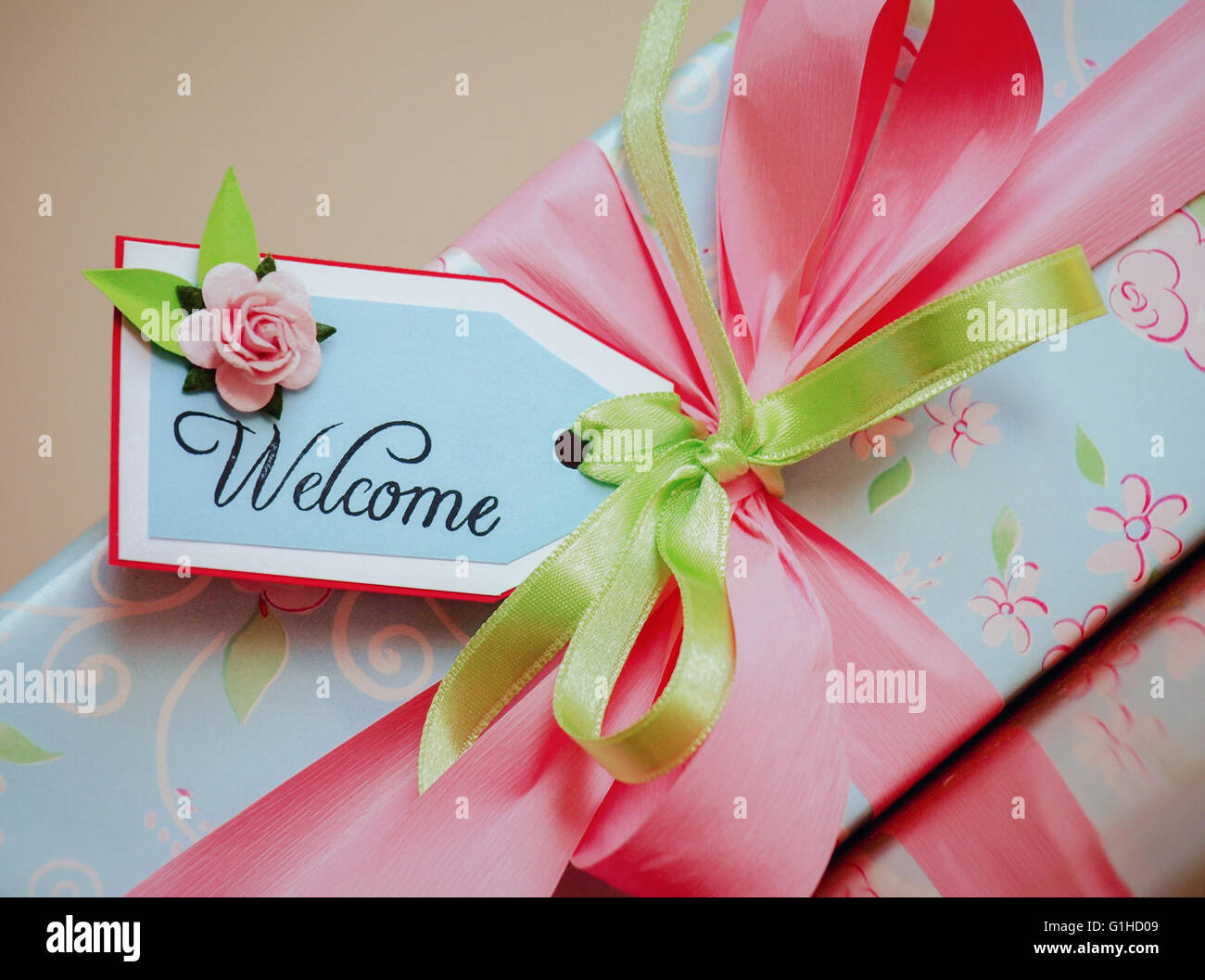 A gift wrapped box in light blue paper with pale pink roses and welcome card Stock Photo
