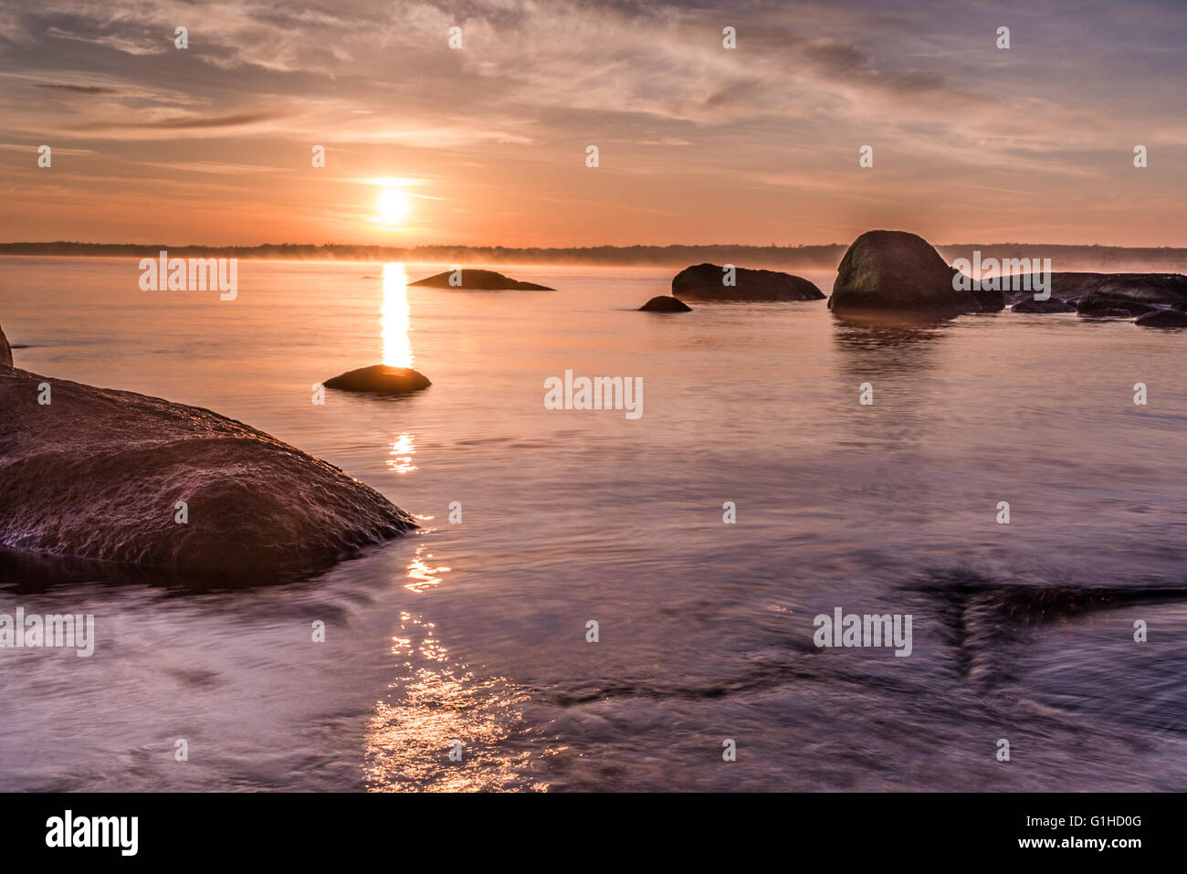 Colorful sunrise over the sea viewed from the beach rocks Stock Photo