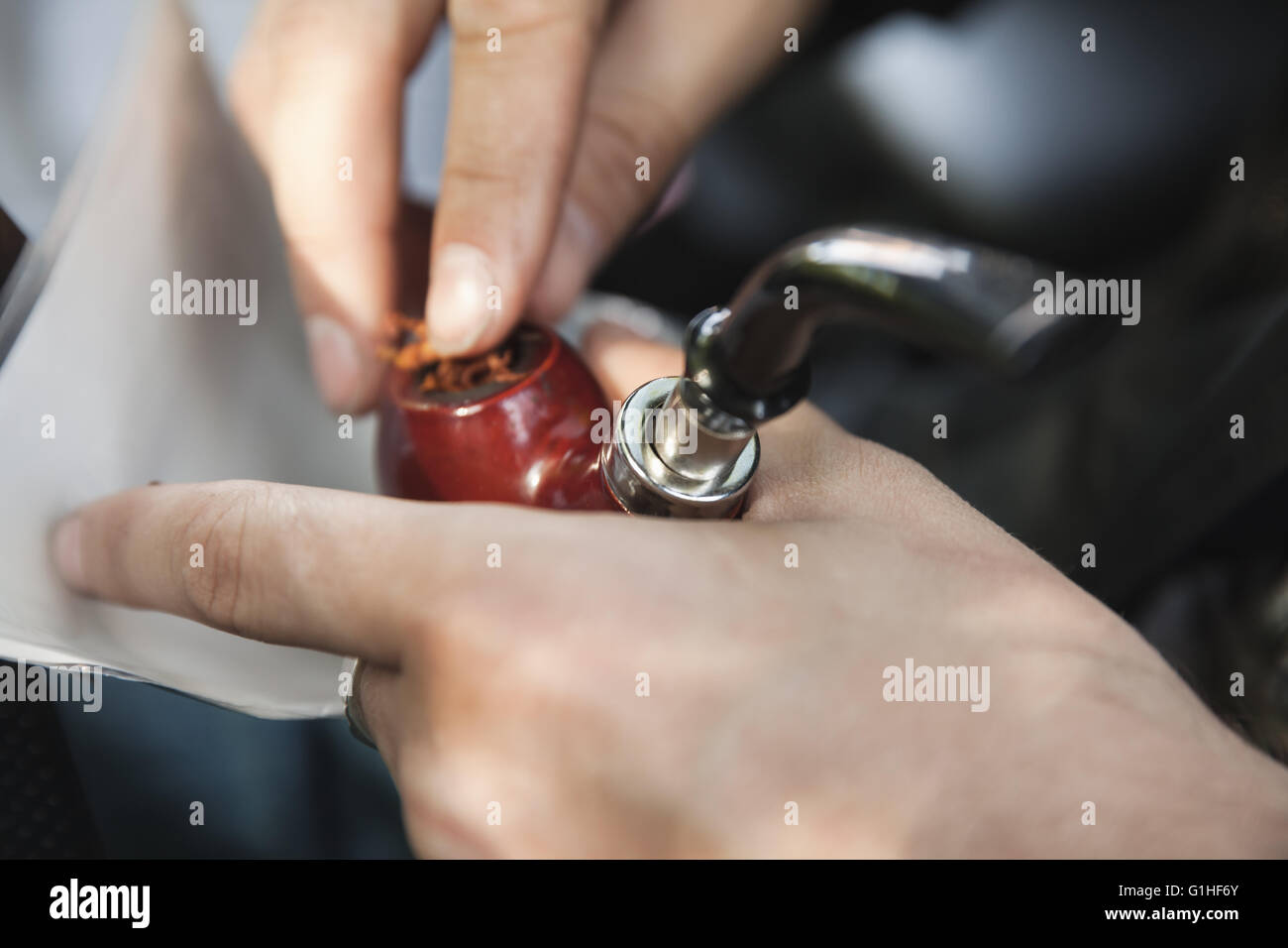 Man fills his pipe with tobacco, close up photo with selective focus on pipe Stock Photo