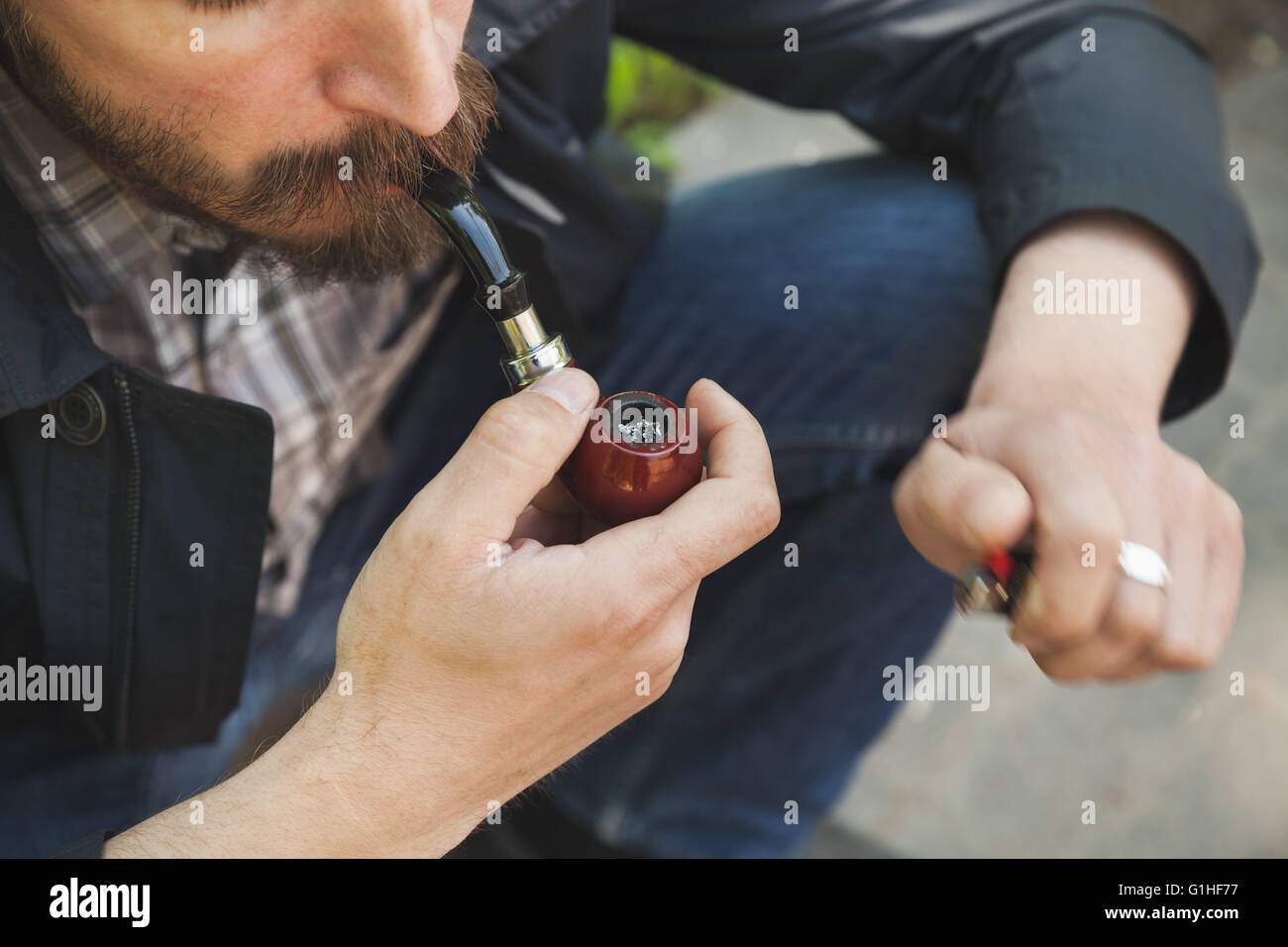 Bearded man smoking pipe, outdoor photo with selective focus Stock Photo