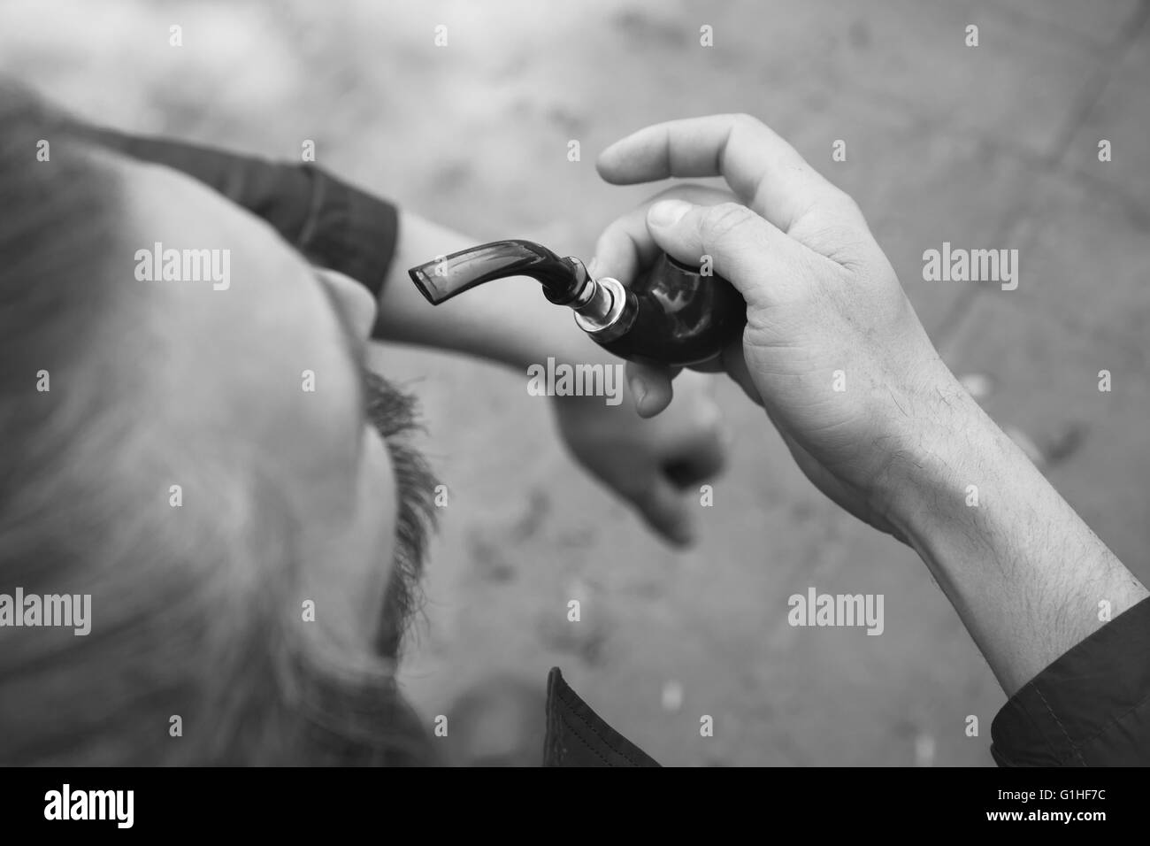 Man smoking pipe, black and white outdoor photo with selective focus Stock Photo