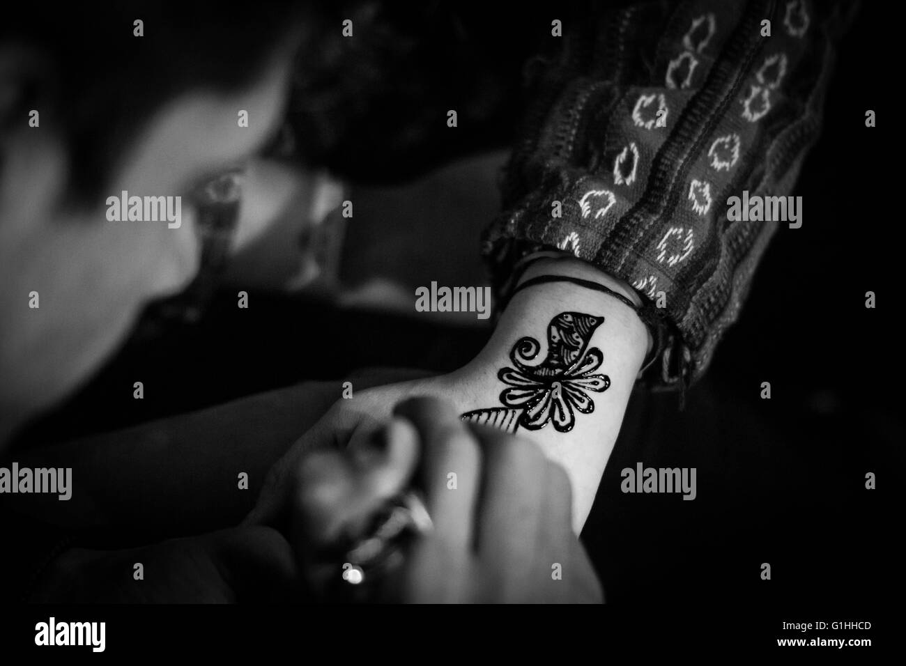 A boy is painting a Mehndi (Henna Tattoo) onto the forearm of a tourist in Thamel, Kathmandu. Stock Photo