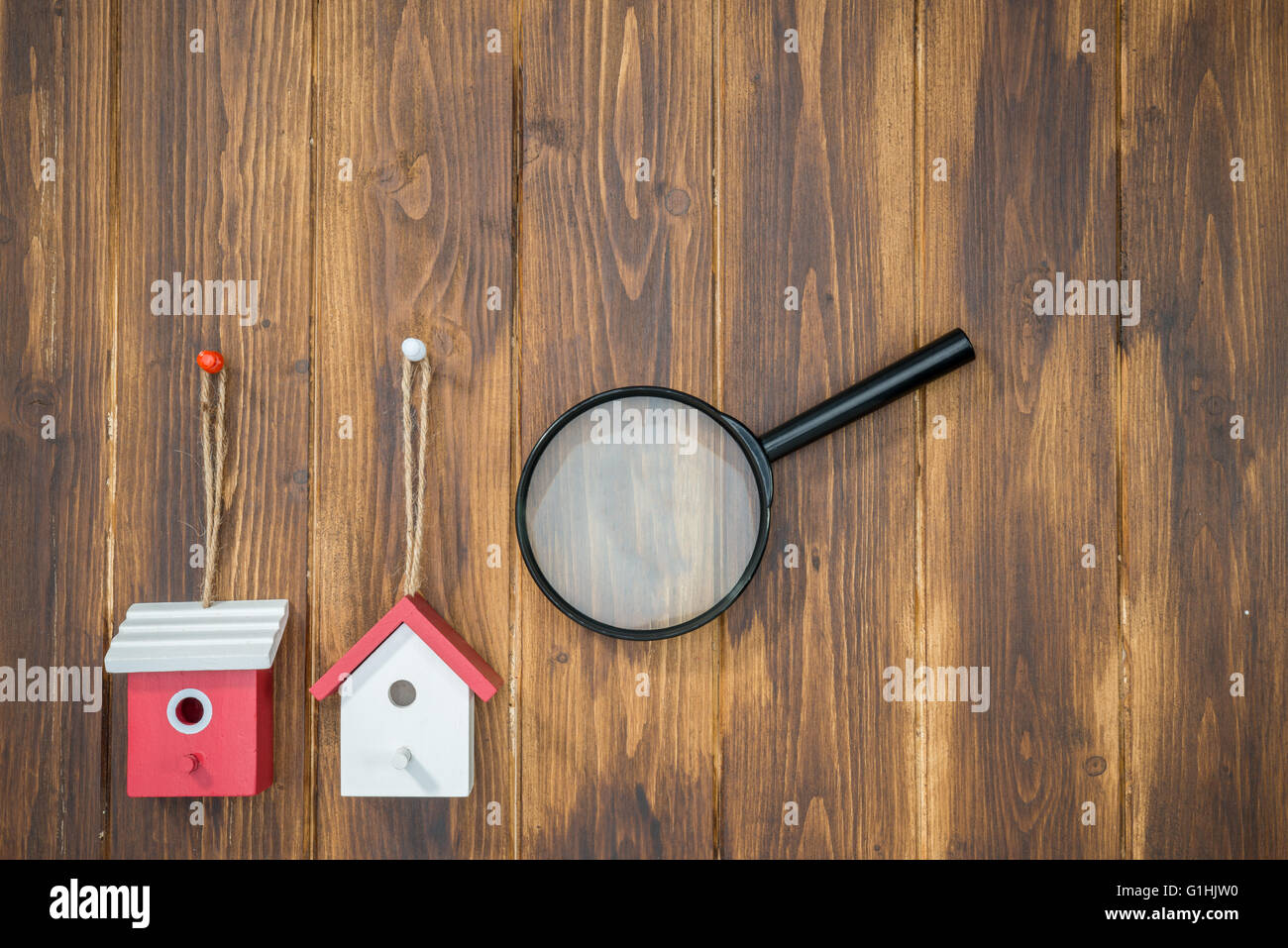 model house with Magnifying Glass on wooden background, House hunting Stock Photo