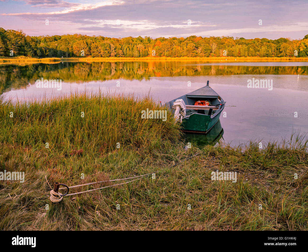 Salt Pond, Eastham MA Cape Cod, Massachusetts, USA solitary wooden boat moored fall color autumn colours reflections in water peaceful scenic Stock Photo
