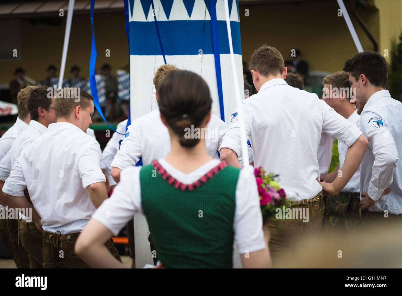 Woman in local dress and young men in leather trouser dancing a traditional bavarian folk dance around a maypole,Bavaria,Germany Stock Photo