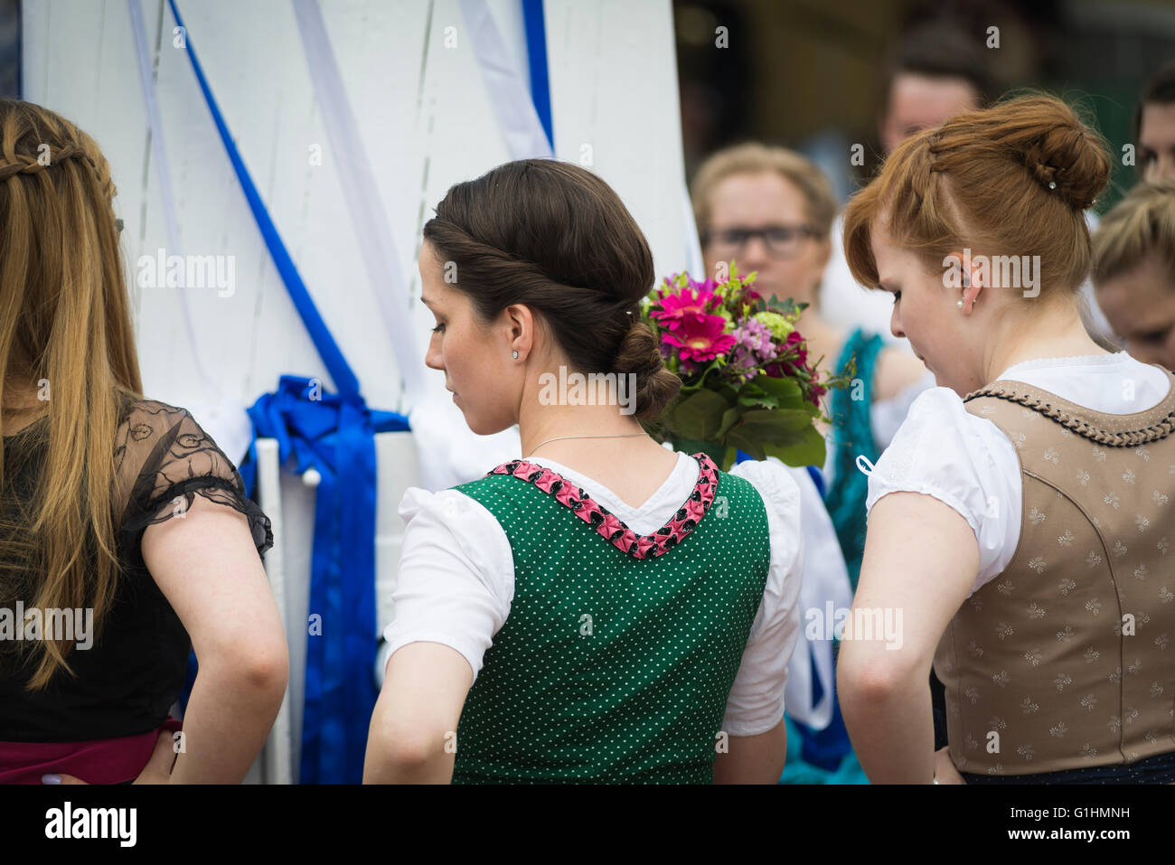 Women in local dresses pause for a moment while dancing a traditional Bavarian folk dance around a maypole,Bavaria,Germany Stock Photo