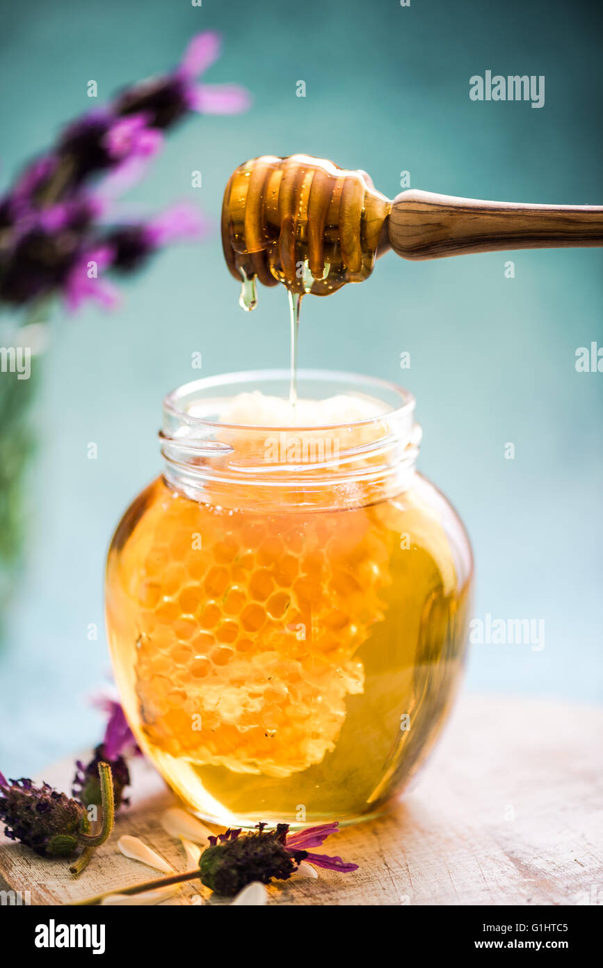 honey dripping to jar with vax comb from wooden dripper Stock Photo