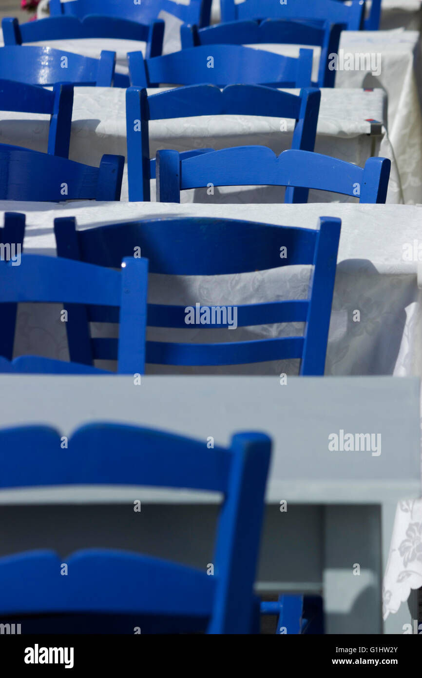Closeup on a row of myconos-blue color painted chairs & empty fish tavern tables. Greece. Stock Photo