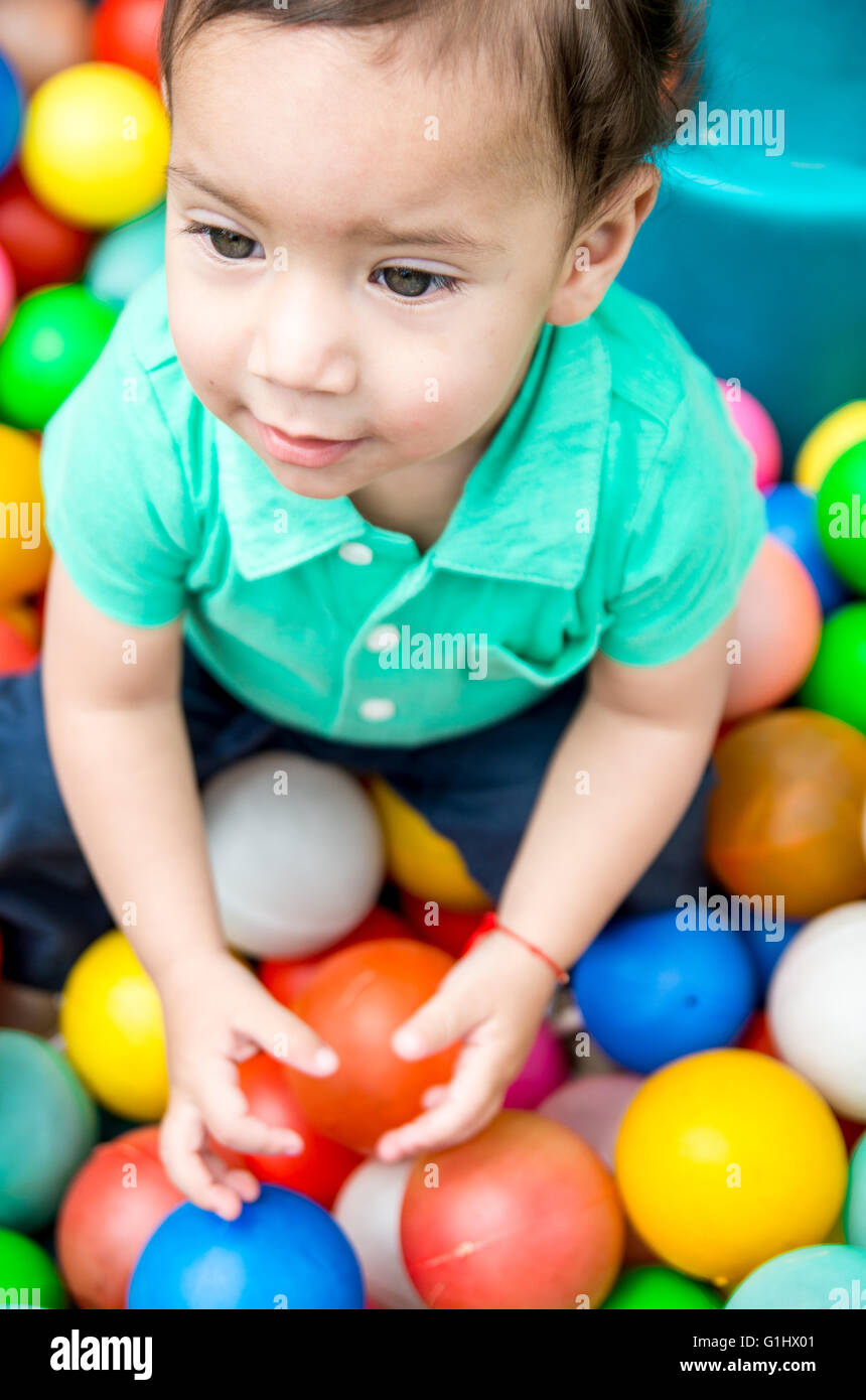 Adorable baby boy wearing turquoise tshirt playing with colored