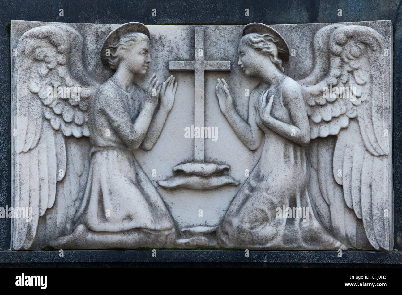 Two kneeling angels depicted in a tombstone at the Monumental Cemetery (Cimitero Monumentale di Milano) in Milan, Lombardy, Italy. Stock Photo