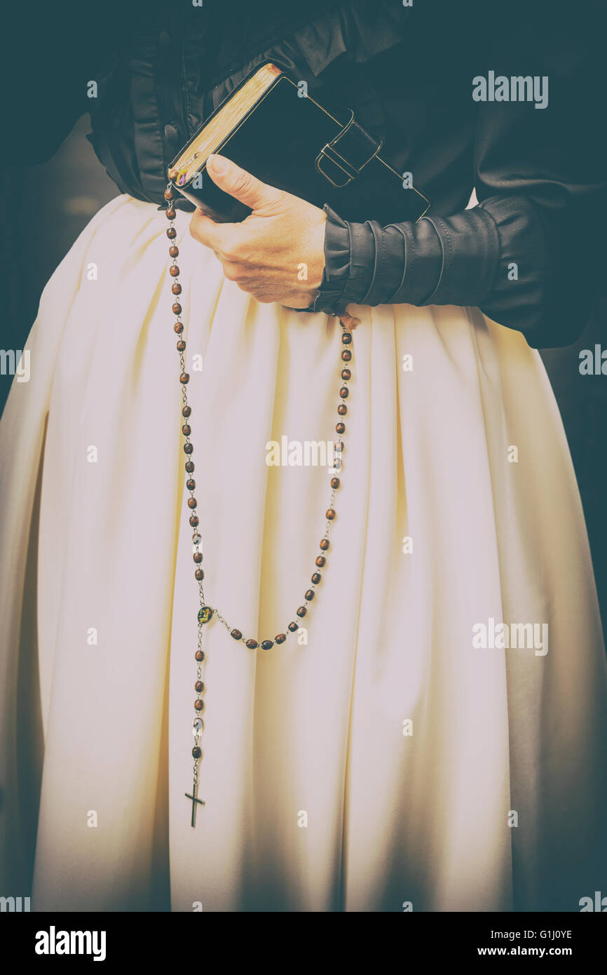 Detail of womans hand holding bible and rosary beads, late 19th century dress. Stock Photo