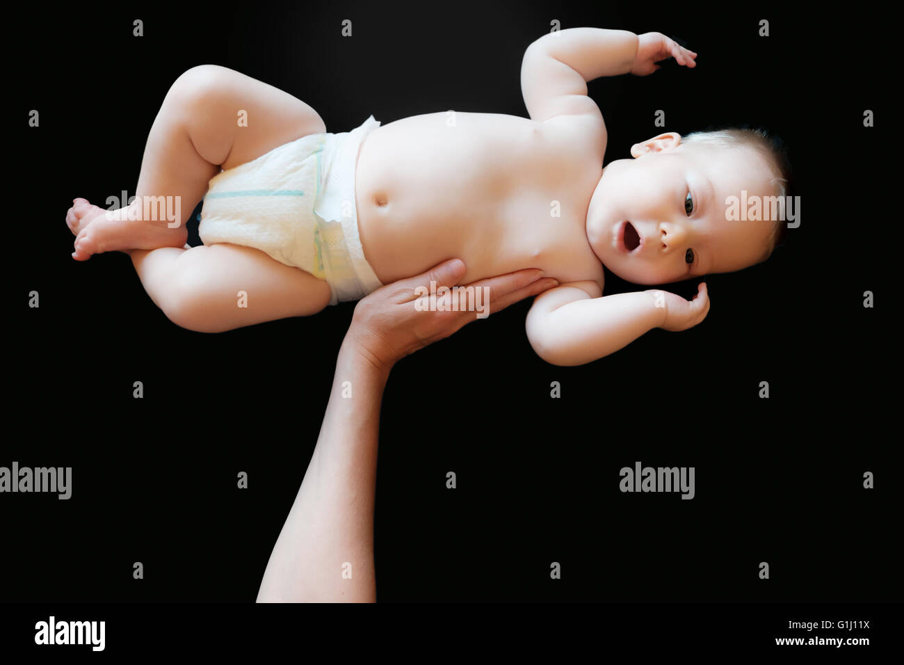 innocent baby lifted in a black background Stock Photo