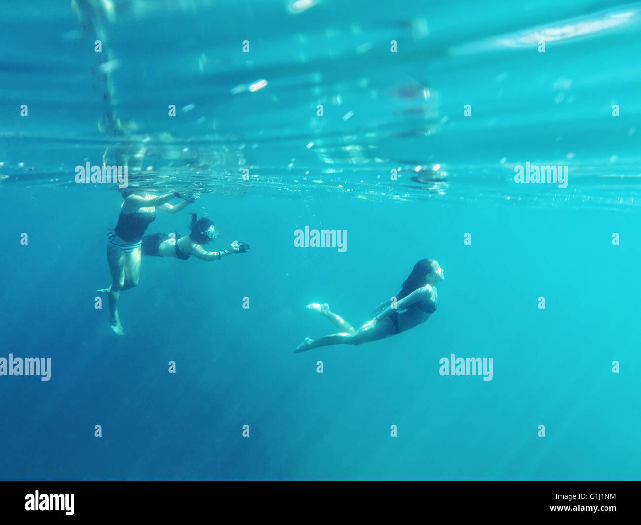 Three people swimming in the ocean Stock Photo