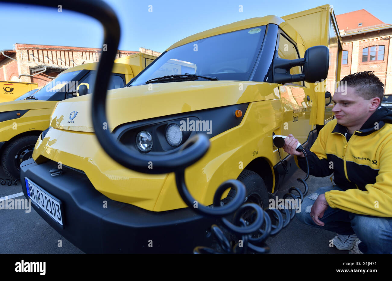 Sven Stein pulls a charging cable of a new electro delivery truck of the Deutsche Post AG in the fleet of the delivery base in Halle/Saale (Saxony Anhalt), Germany, 21 April 2016. Since the middle of the month, the StreetScooters have been used for the mail and parcel delivery in the Halle region. The Deutsche Post DHL Group has developed this vehicle type together with the StreetScooter GmbH and the RWTH Aachen University. Photo: Hendrik Schmidt/dpa Stock Photo