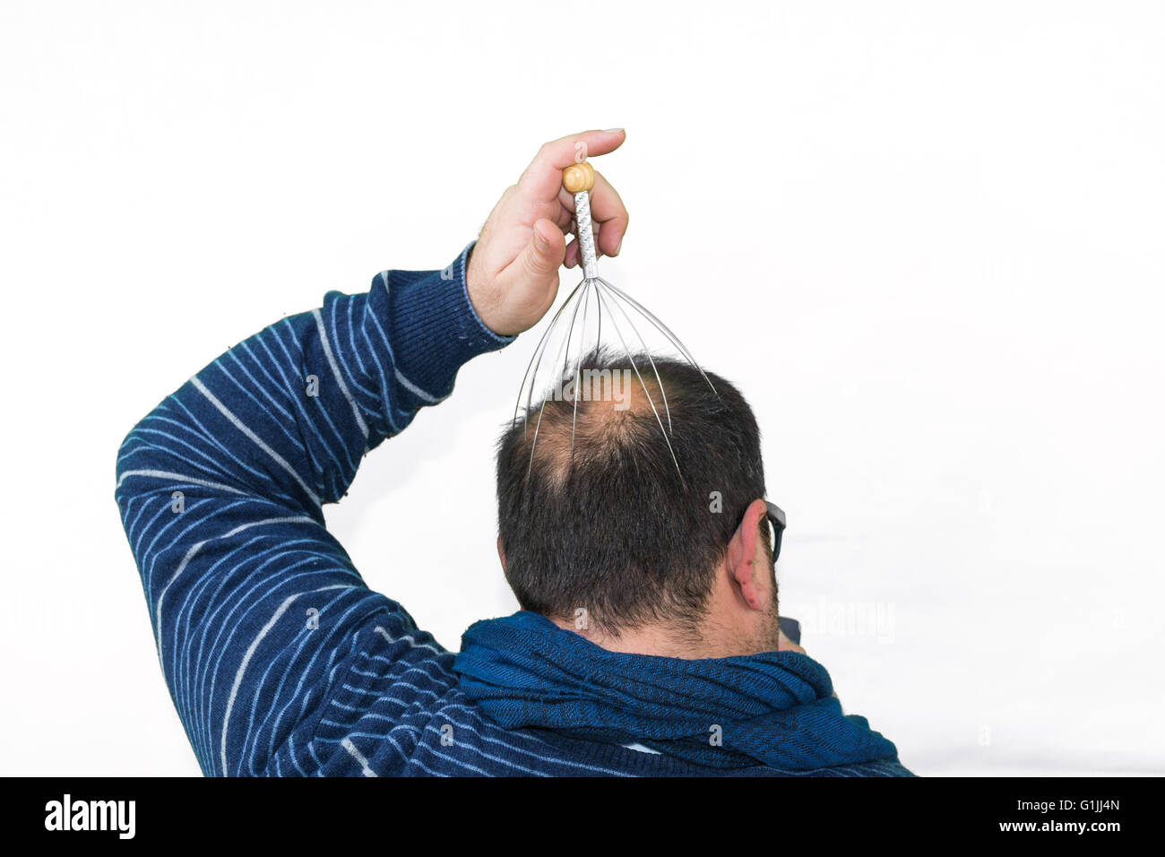 Man relaxes with the Genie head massager. Alternative Therapy. Indian head massage tool, self head massager. Stock Photo