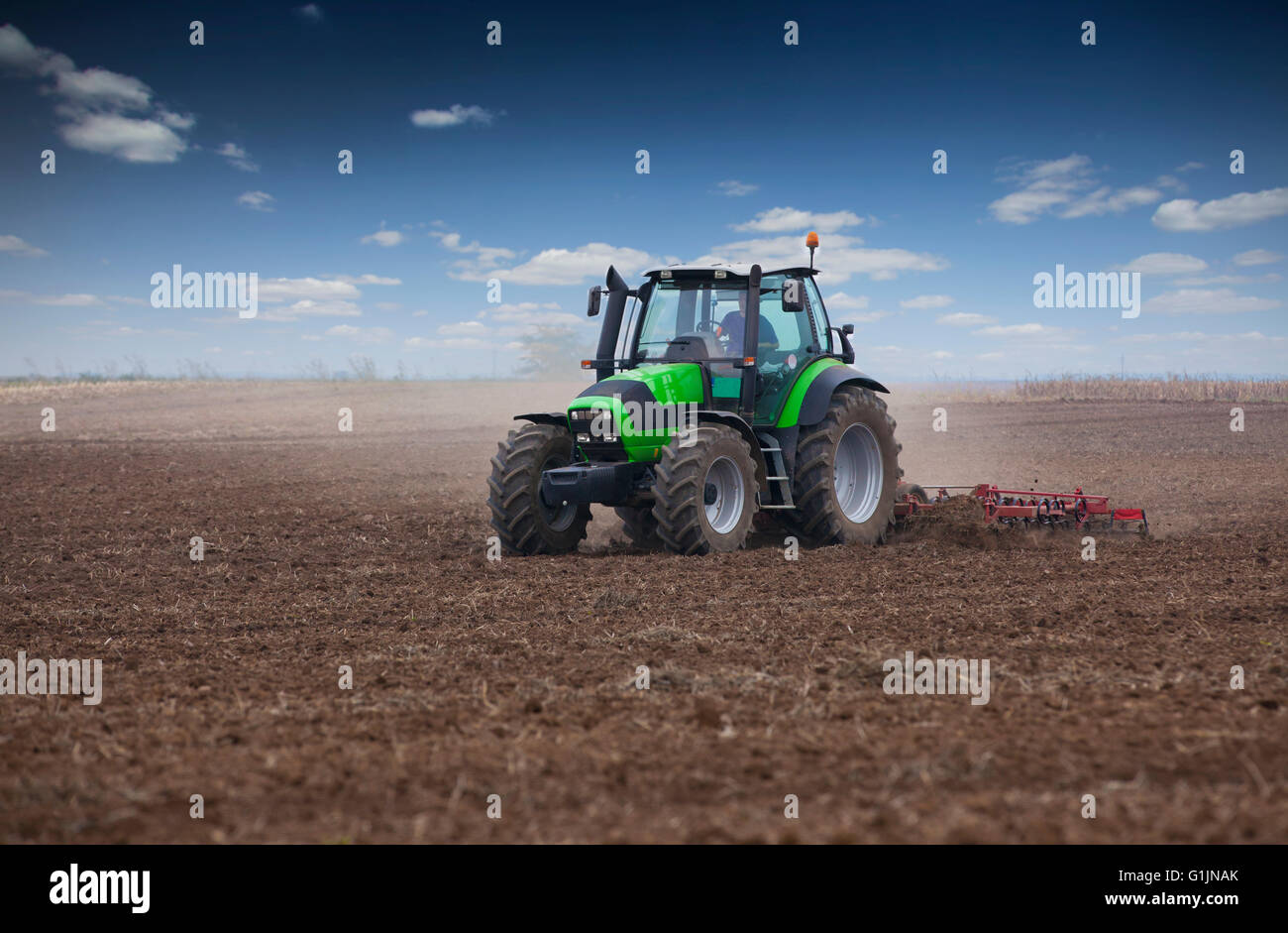 Young farmer in tractor preparing land for sowing Stock Photo